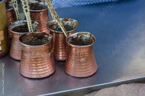 Fototapeta Naklejka Na Ścianę i Meble -  Coffee copper pots in sand. Traditional turkish coffee prepared on hot sand 