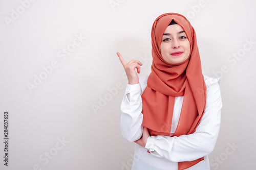 Hijab muslim woman pointing finger to blank copy space area, girl pointing fingers up and looking camera