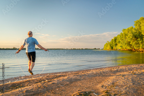 senior man jumping rope on a beach