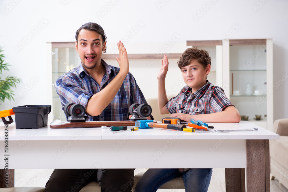 Obraz premium Young father repairing skateboard with his son at home