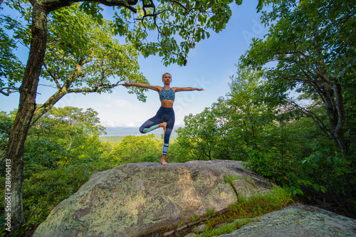 Young woman practicing yoga standing in tree pose outdoors harmony with nature.