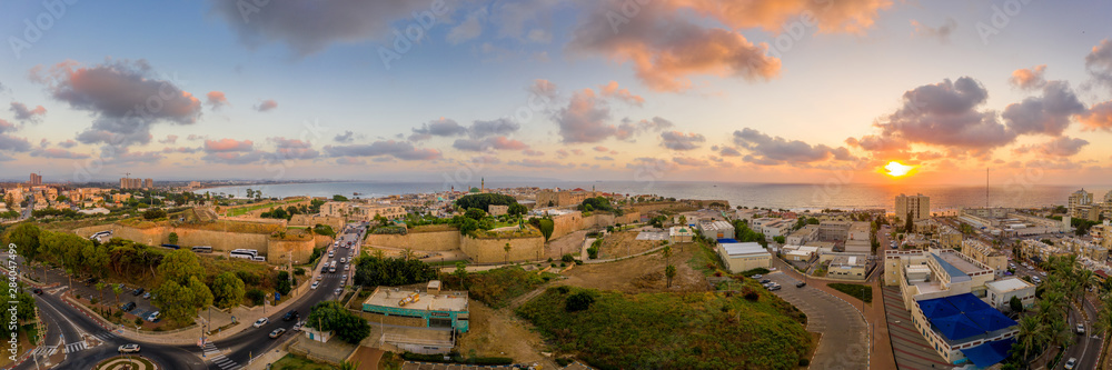 Fototapeta premium Aerial summer sunset view of Acco, Acre, Akko medieval old city with green roof Al Jazzar mosque and crusader palace, city walls, arab market, knights hall, crusader tunnels, in Israel
