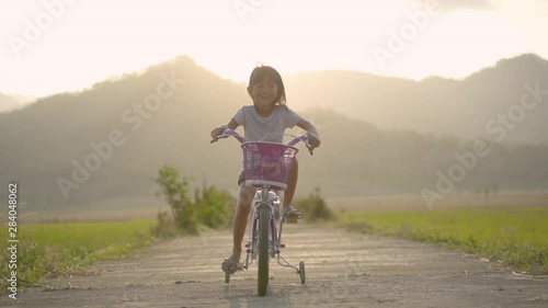 toddler enjoy riding her bicycle outdoor in beautiful day photo