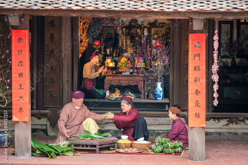 Vietnamese family members making Banh Chung together on old-styled house yard. Chung cake is a very well-known dish that could never miss on the altar, and family meal of Vietnamese during Tet holiday photo