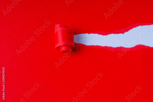 Torn red coloured paper on white background with closeup hole in the sheet of paper. Background concept with copy space. photo