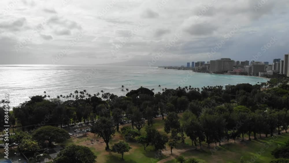 Beautiful Aerial of Waikiki City and Beach on Oahu Hawaii. Shot is moving upwards. Starting from park with trees, later exposing the beach and the ocean. Beautiful Aerial of Waikiki City and Beach on Oahu Hawaii. Shot is moving upwards. Starting from park with trees, later exposing the beach and the ocean.