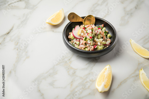 Norddeutscher Friesischer Nordseekrabben Salat in Schale mit Gurken, Radieschen, Zwiebeln, Dill und Zitronen auf Marmor Tisch photo