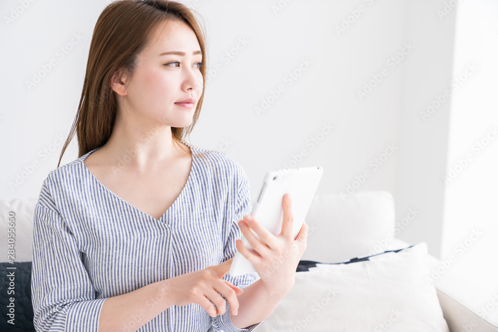 部屋でタブレットを見る女性 部屋でタブレットを見る女性