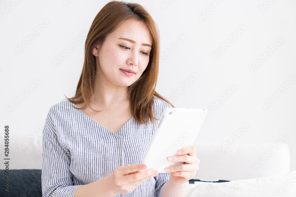 部屋でタブレットを見る女性 部屋でタブレットを見る女性