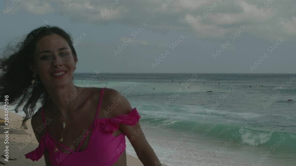 Beautiful tanned fitness woman in pink bikini spending free time at the beach - video in slow motion Beautiful tanned fitness woman in pink bikini spending free time at the beach - video in slow motion