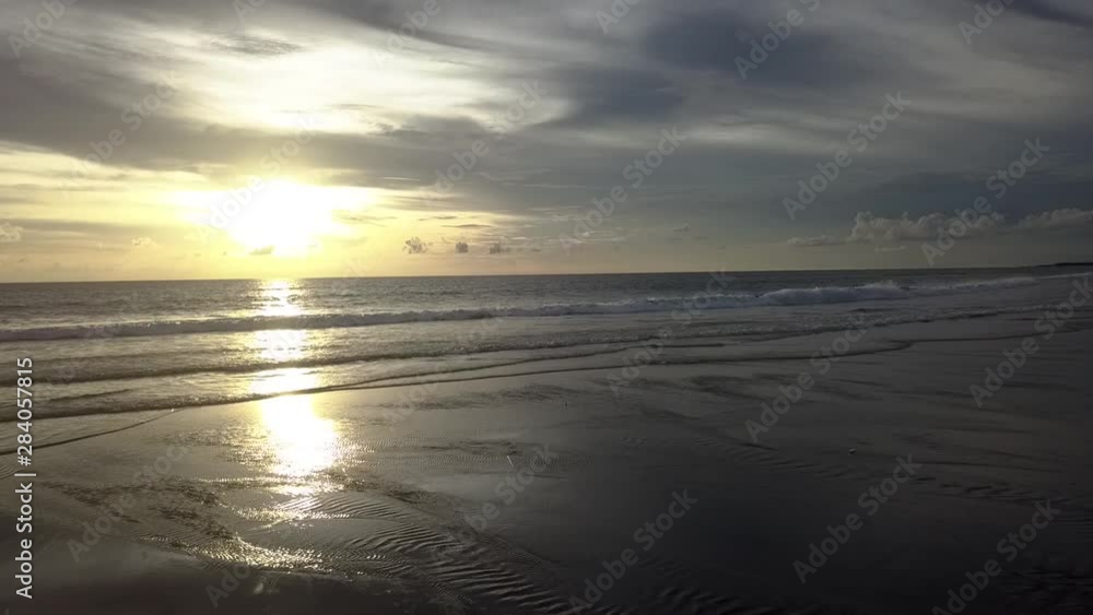 AERIAL DOLLY BACKWARD at Calm waves on Sunset on desert beach, sunlight reflect on water surface. Cinematograph skyline. AERIAL DOLLY BACKWARD at Calm waves on Sunset on desert beach, sunlight reflect on water surface. Cinematograph skyline.
