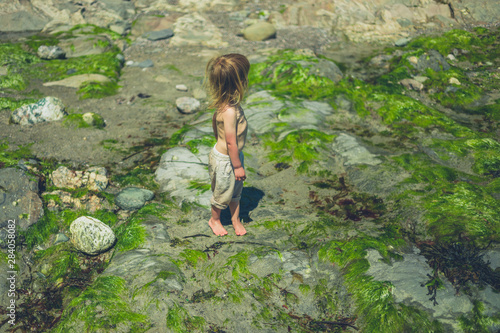 Little toddler standing on the beach in summer