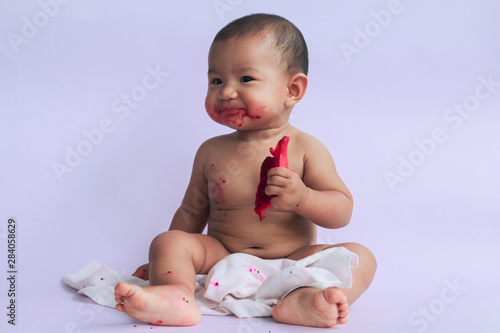 asian cute baby girl eating red dragon fruit. newborn baby on white background