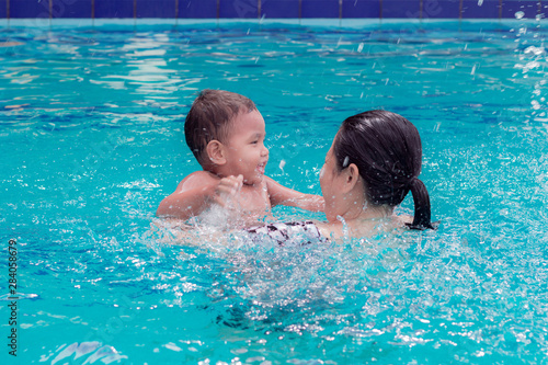 asian mother and baby in swimming pool.  little baby having fun in a swimming pool at thailand