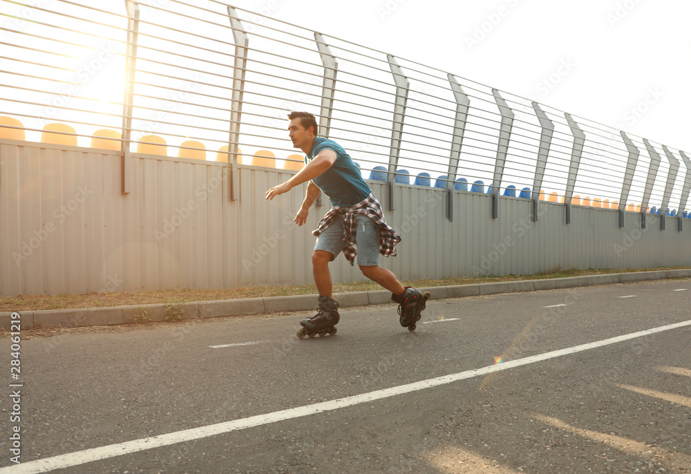 Handsome young man roller skating outdoors. Recreational activity