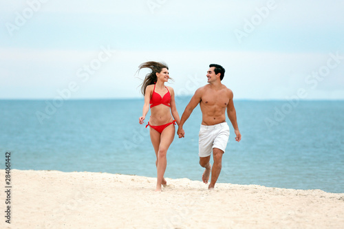 Happy young couple running together on sea beach