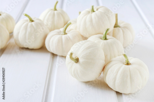 Baby boo pumpkins on white wooden table.