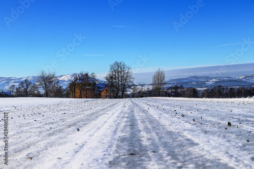 Frozen forest road sprinkled with gravel in foothills of Beskydy mountains in Czech republic. Typical winter day. Countryside view. Gorgeous snow cover.