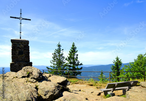 Cross and wooden bench on the summit of a mount Grosser Falkenstein in the National park Bayerische Wald, Germany. photo