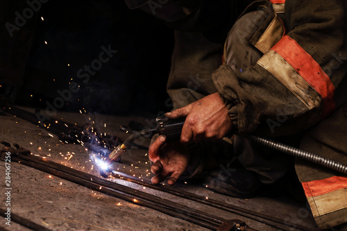 Man welding in garage. Manual welding, sparks, iron.