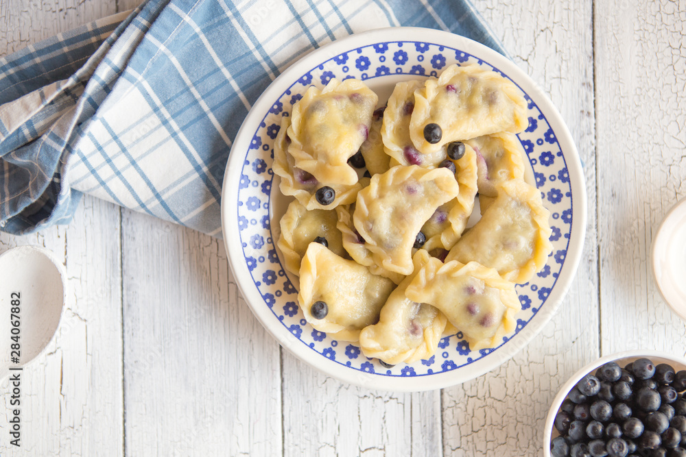 blueberry dumplings, pierogi, vareniki in a clay bowl on a old kitchen table, view from above, flat lay, copy space left blueberry dumplings, pierogi, vareniki in a clay bowl on a old kitchen table, view from above, flat lay, copy space left