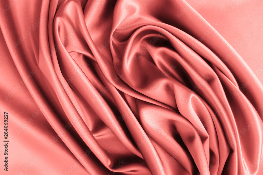 Obraz premium Smooth elegant wavy coral pink satin silk luxury cloth fabric texture, abstract background design.