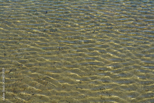 Ripples on the surface of the sea water with sun highlights.