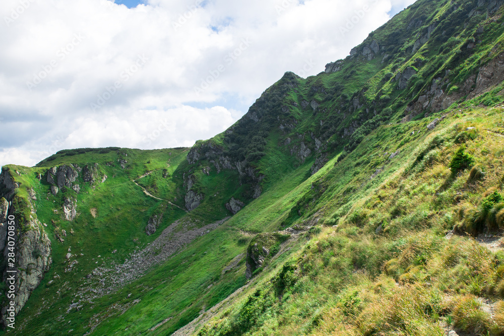 Naklejka premium green mountain alps ridge, low gray clouds