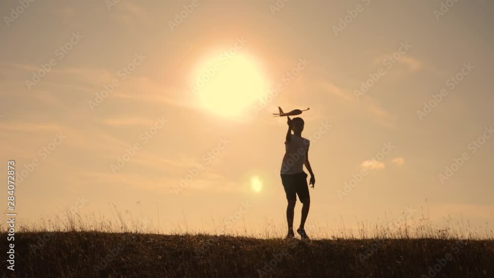 Two boys play with a wooden plane at sunset. Silhouette of children playing with an airplane. Dreams of flying. Children concept. Teamwork. Games and teamwork Two boys play with a wooden plane at sunset. Silhouette of children playing with an airplane. Dreams of flying. Children concept. Teamwork. Games and teamwork