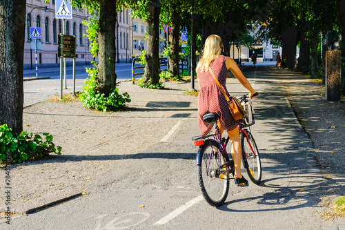 Woman rides a bicycle on a bike lane in Sweden. Girl is riding her bike on the way to Stockholm center.