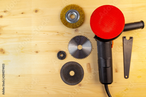 Flat lay view of a workbench with a set of tools consisting of anangle grinder with polishing disc on and a spare cutting discs for metal, wood and brushing photo