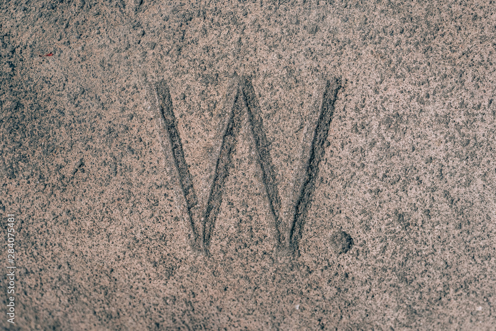 Sign W carved on the stone. Letter of the alphabet on granite. Stone ...