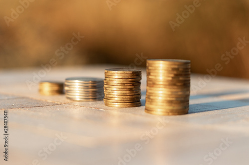 Stacks of coins laying down on the table on the beautiful sunset background, economy growth and strategy concept