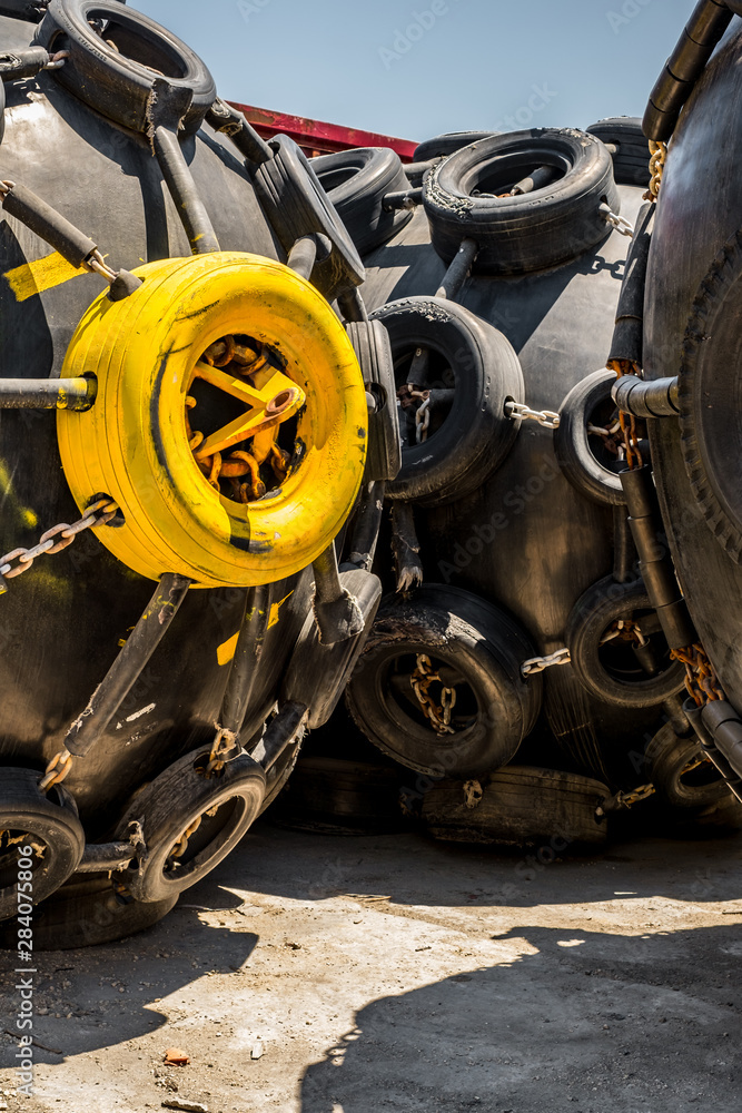 Fototapeta premium A huge Marine Pneumatic heavy rubber fender surrounded by tires fixed with chains.