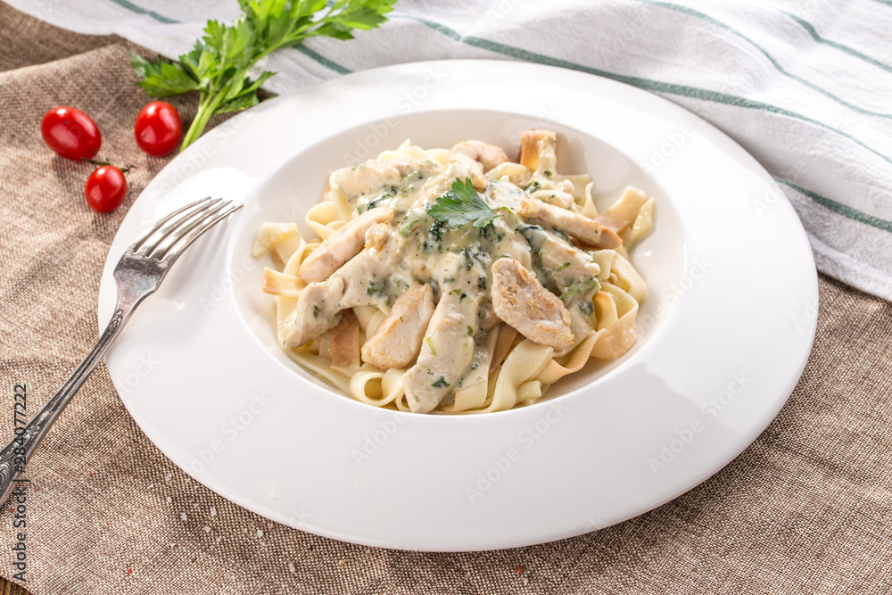 fettuccine pasta with chicken and cheese sauce on white plate on tablecloth