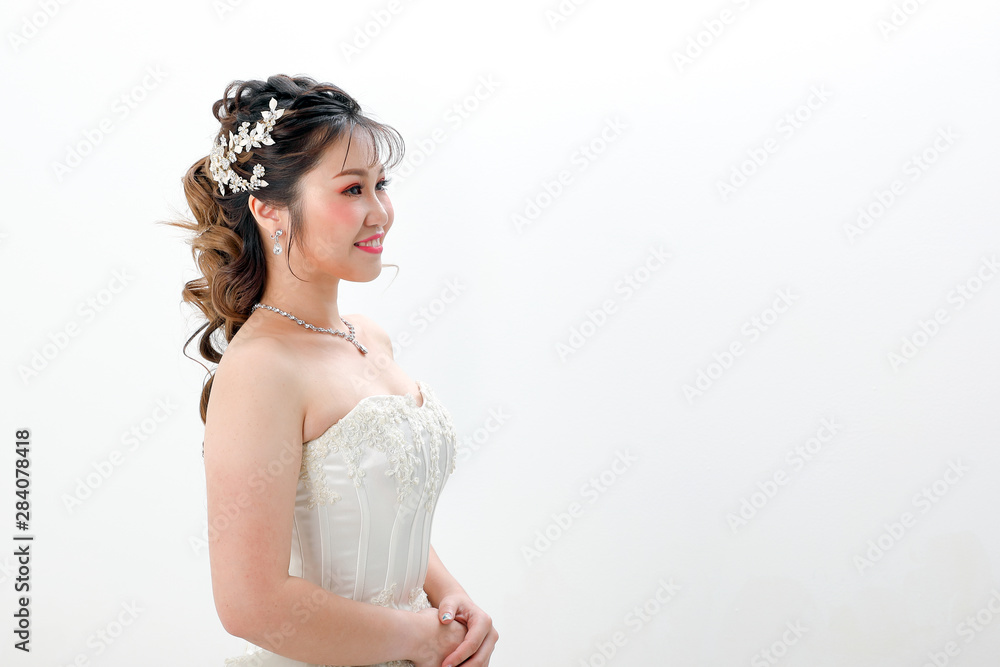 Young Asian woman in white dress hair done with crown on white background Young Asian woman in white dress hair done with crown on white background
