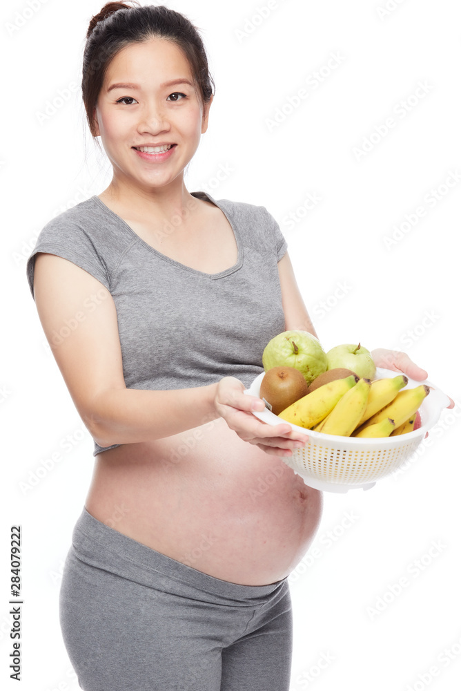 A portrait of a Happy pregnant woman with a bowl of fruits A portrait of a Happy pregnant woman with a bowl of fruits