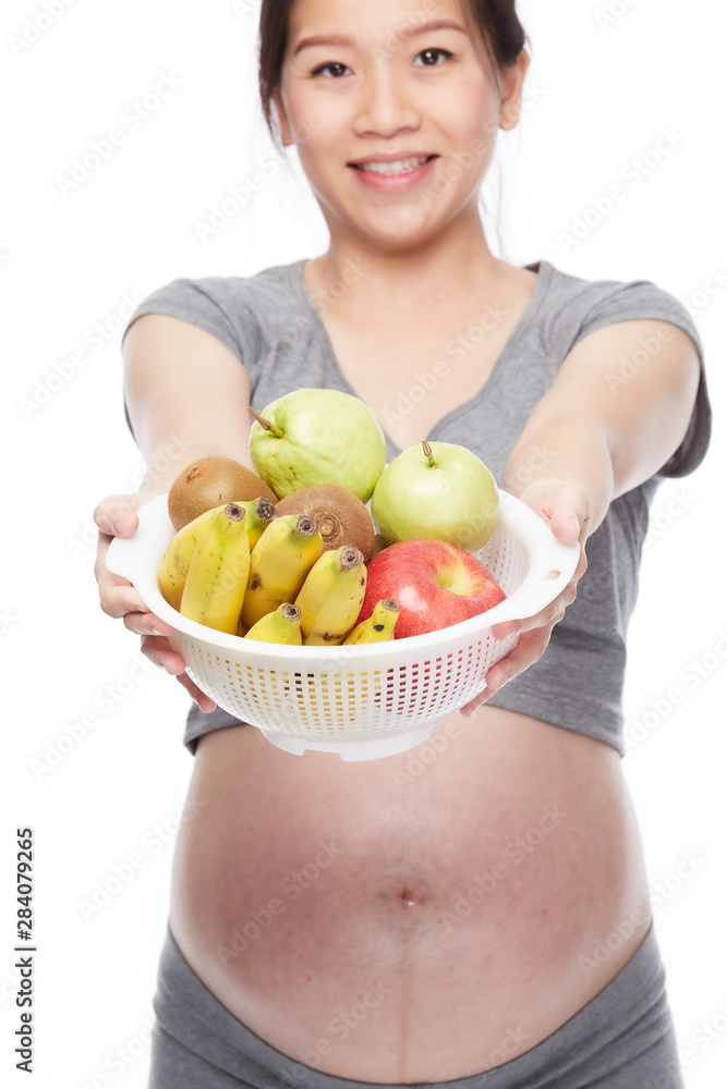 A portrait of a Happy pregnant woman with a bowl of fruits A portrait of a Happy pregnant woman with a bowl of fruits