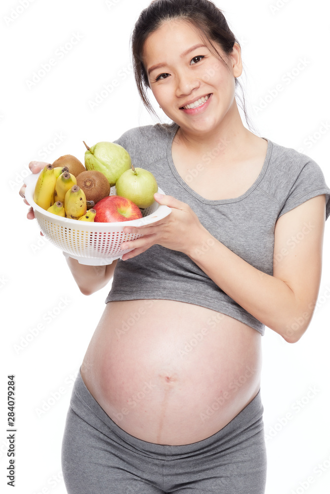 A portrait of a Happy pregnant woman with a bowl of fruits A portrait of a Happy pregnant woman with a bowl of fruits