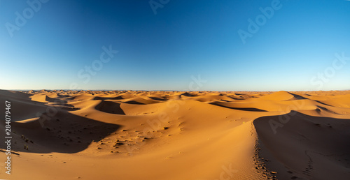 Sand dunes in Morocco, desert landscape, sand texture, tourist camp for night stay, panorama view of sunset over Sahara