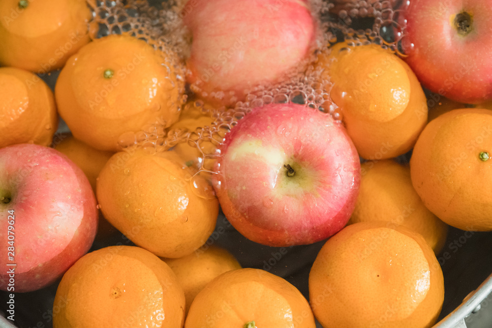 Hands washing fresh orange and apple. Hands washing fresh orange and apple.