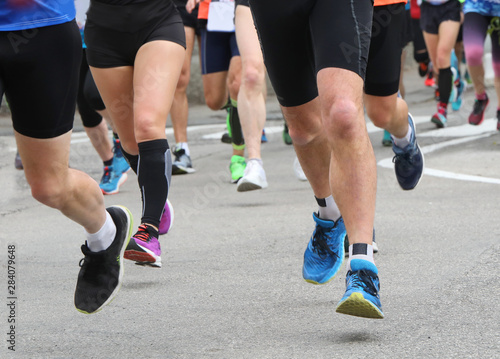 legs of runners during a race on the road