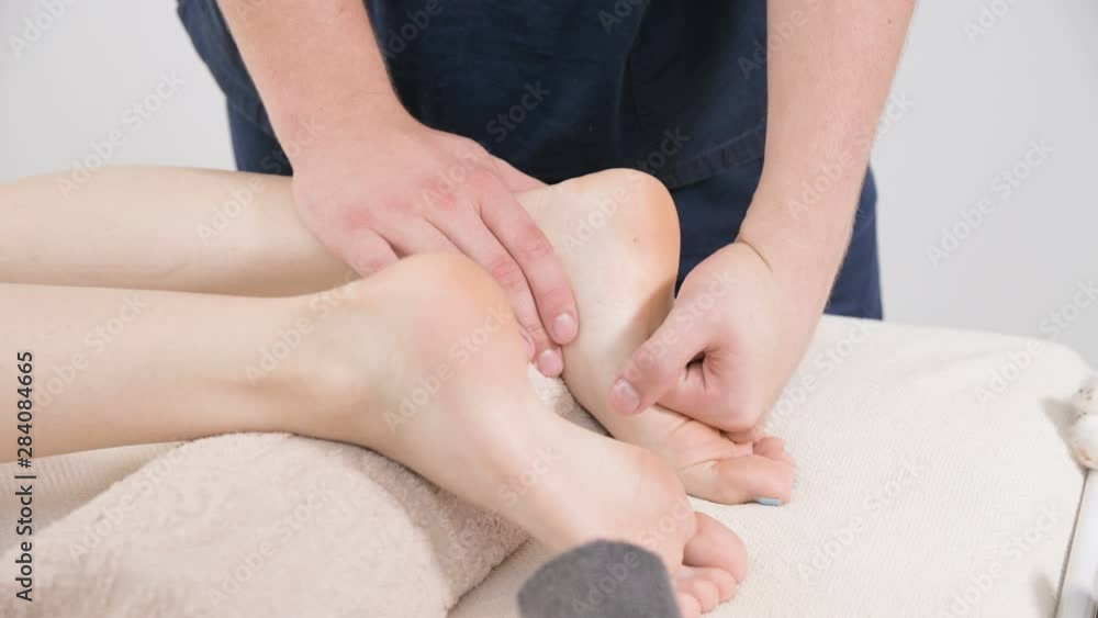 Close-up of a male physiotherapist doing foot and heels foot massage to a young woman in a beauty and health spa. Foot and body care concept Close-up of a male physiotherapist doing foot and heels foot massage to a young woman in a beauty and health spa. Foot and body care concept