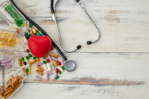 Top view of red heart and medicine on wooden floor