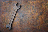 Old rusty wrench lying on the rusty textured metal background. Mechanic background