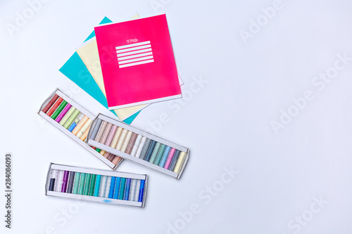 Flatlay childrens and school accessories notebooks and colored pencils over white background - Back to school concept. Copy space. Place for text.
