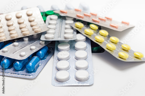 Packs of pills with tablets. A pile of pills in blister packs. Blister packs full of multi-colored pills isolated on a white background. Full colored pills package. Pharmaceutical blister pack.