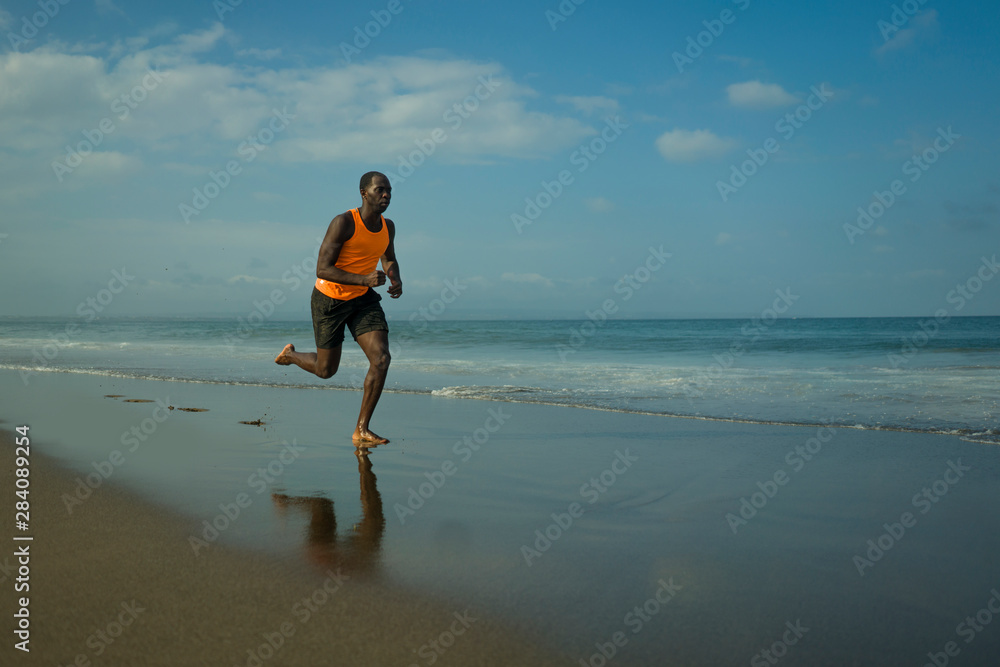 athletic full body portrait of young attractive and fit black afro American man running on the beach doing Summer fitness jogging workout at the sea in healthy lifestyle concept athletic full body portrait of young attractive and fit black afro American man running on the beach doing Summer fitness jogging workout at the sea in healthy lifestyle concept