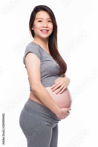 Happy asian pregnant woman smiling and touching her belly