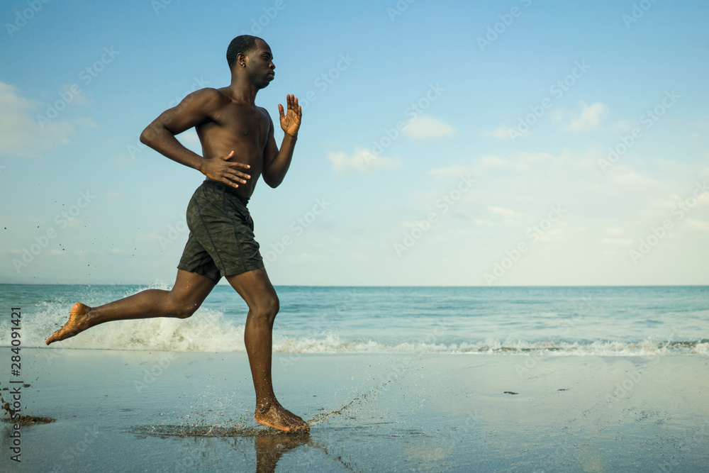 Young athletic man with fitness body standing on the beach Stock